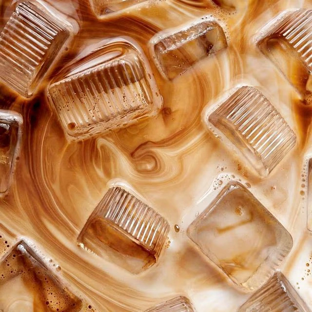 Glass filled with iced coffee topped with ice cubes.